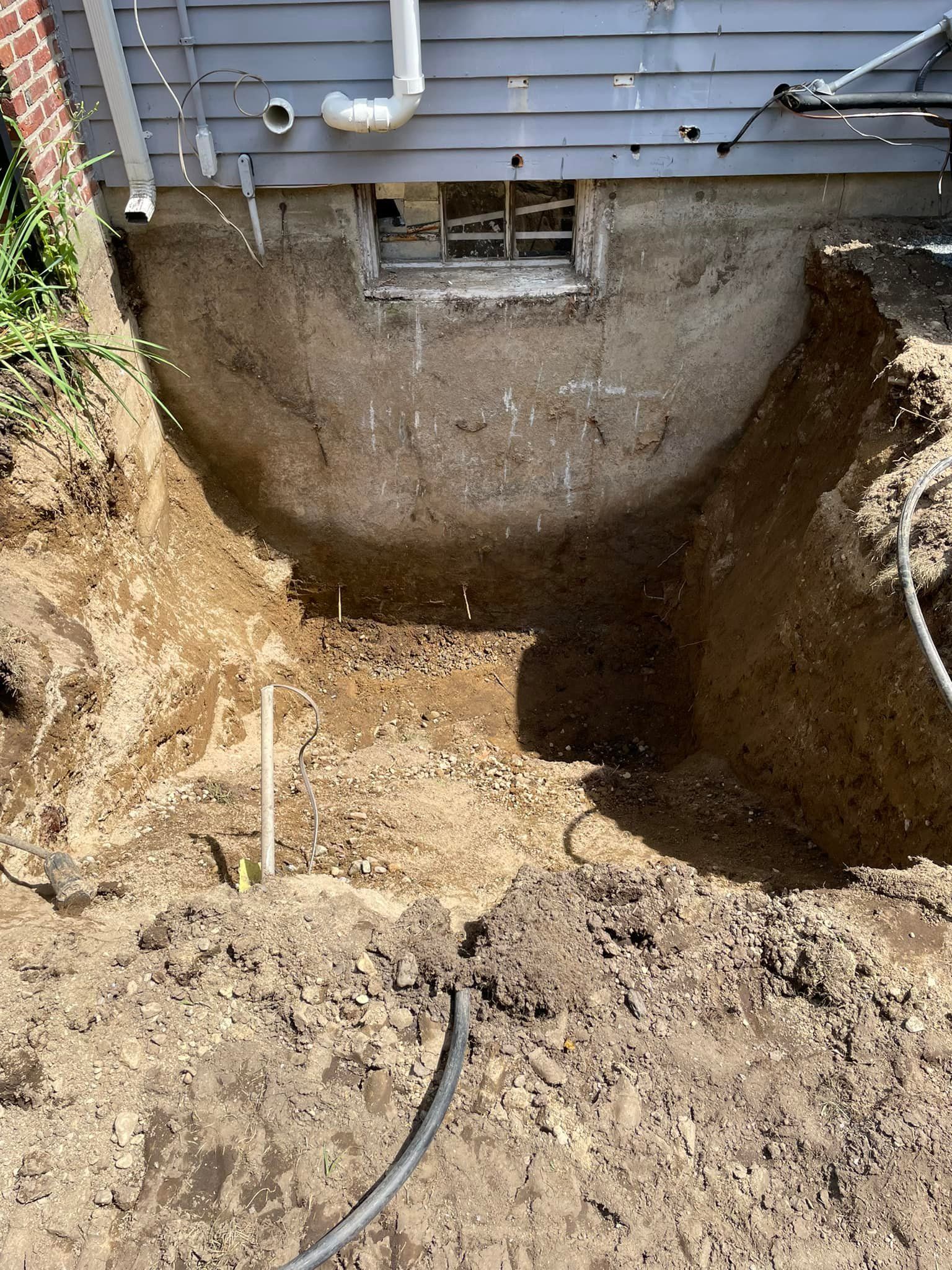 A large hole in the ground in front of a house.