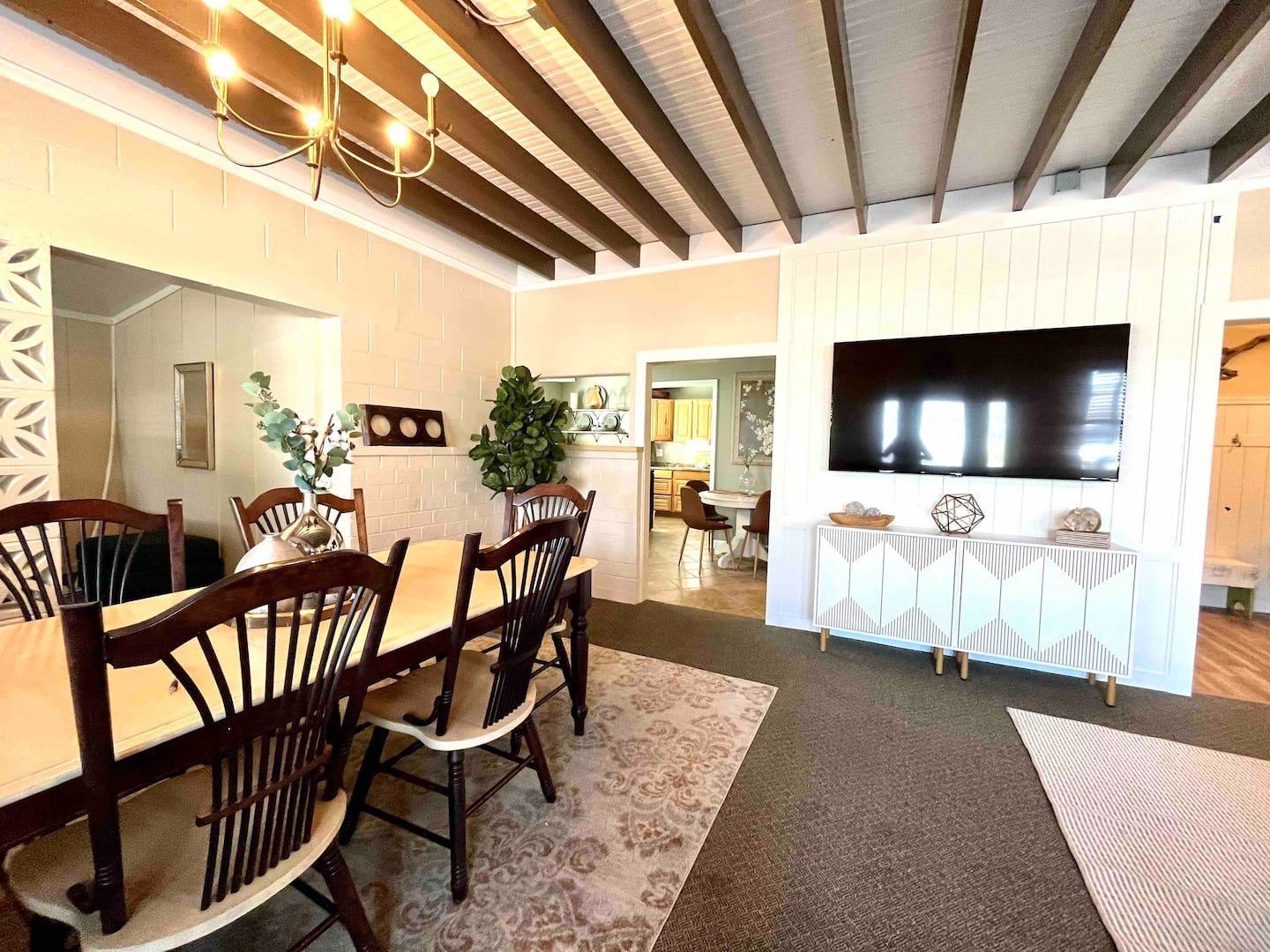 A dining room with a table and chairs and a flat screen tv on the wall.