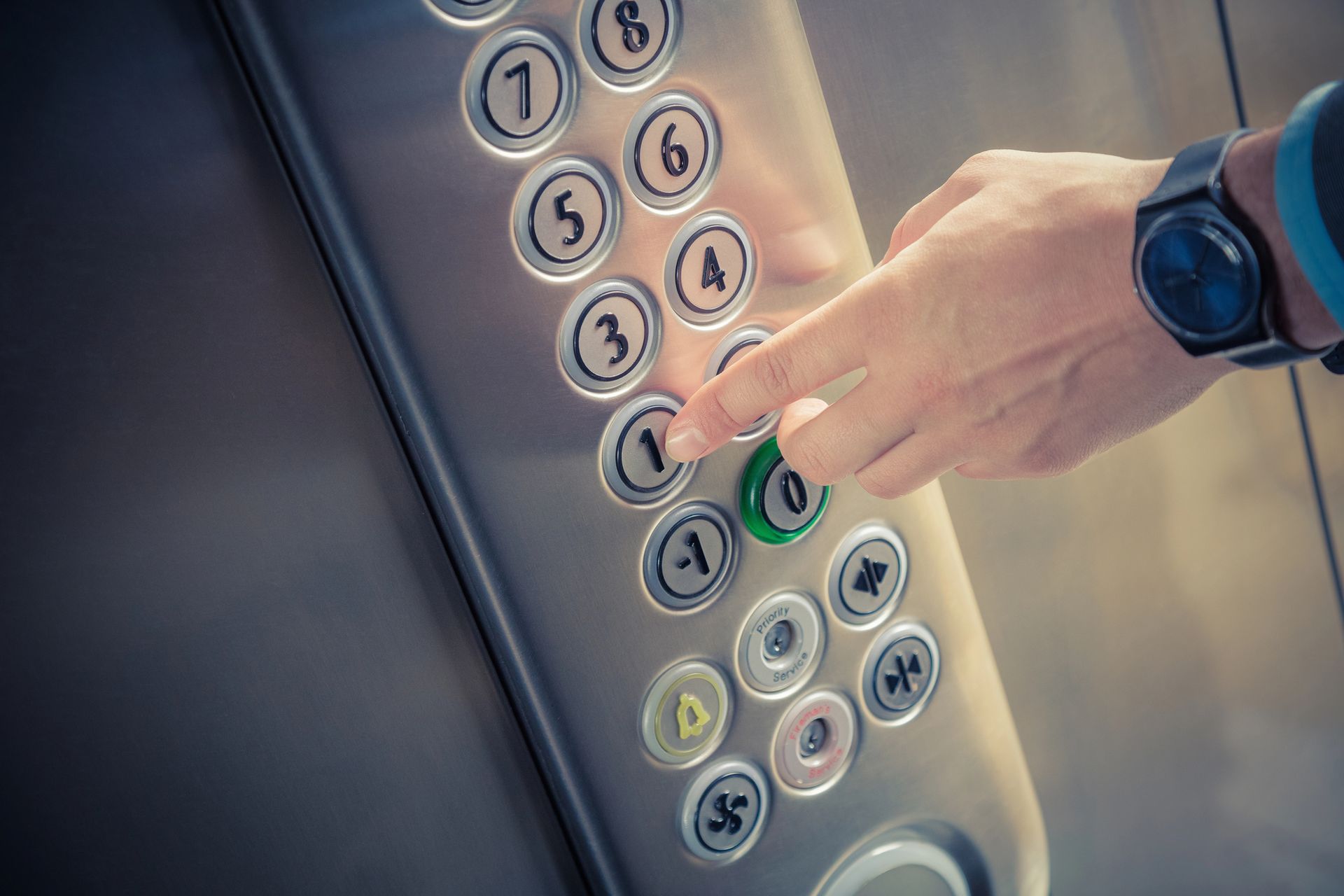 Mano presionando un panel de control de ascensor iluminado con botones numerados