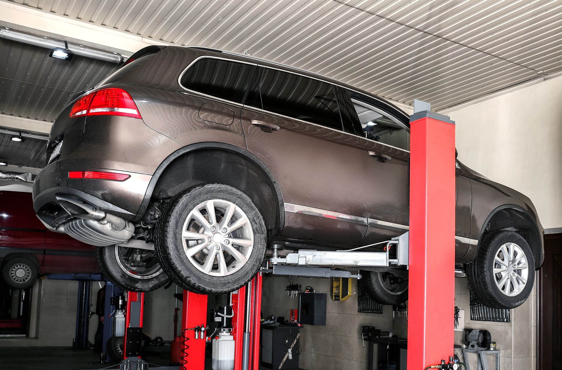Un SUV oscuro elevado en un elevador de coches en un taller de reparación de automóviles.