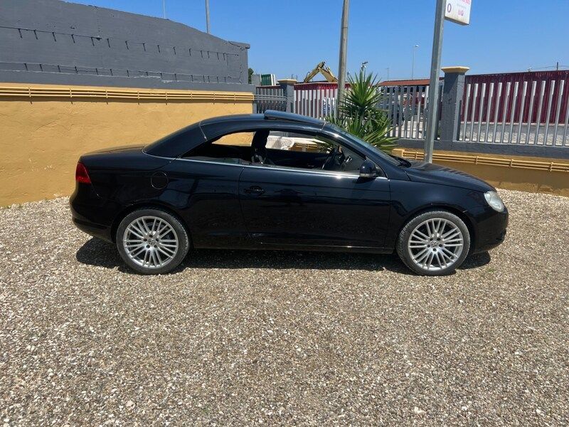 un'auto nera è parcheggiata sul lato di una strada vicino all'oceano al tramonto.
