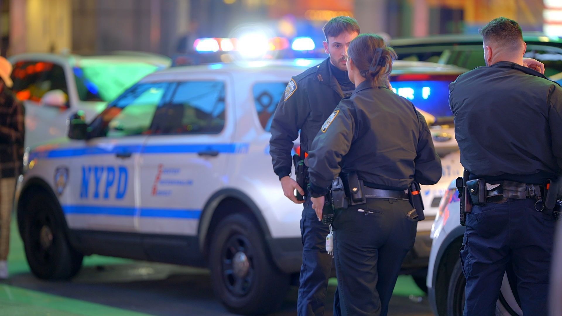 A group of police officers standing in front of a nypd car.