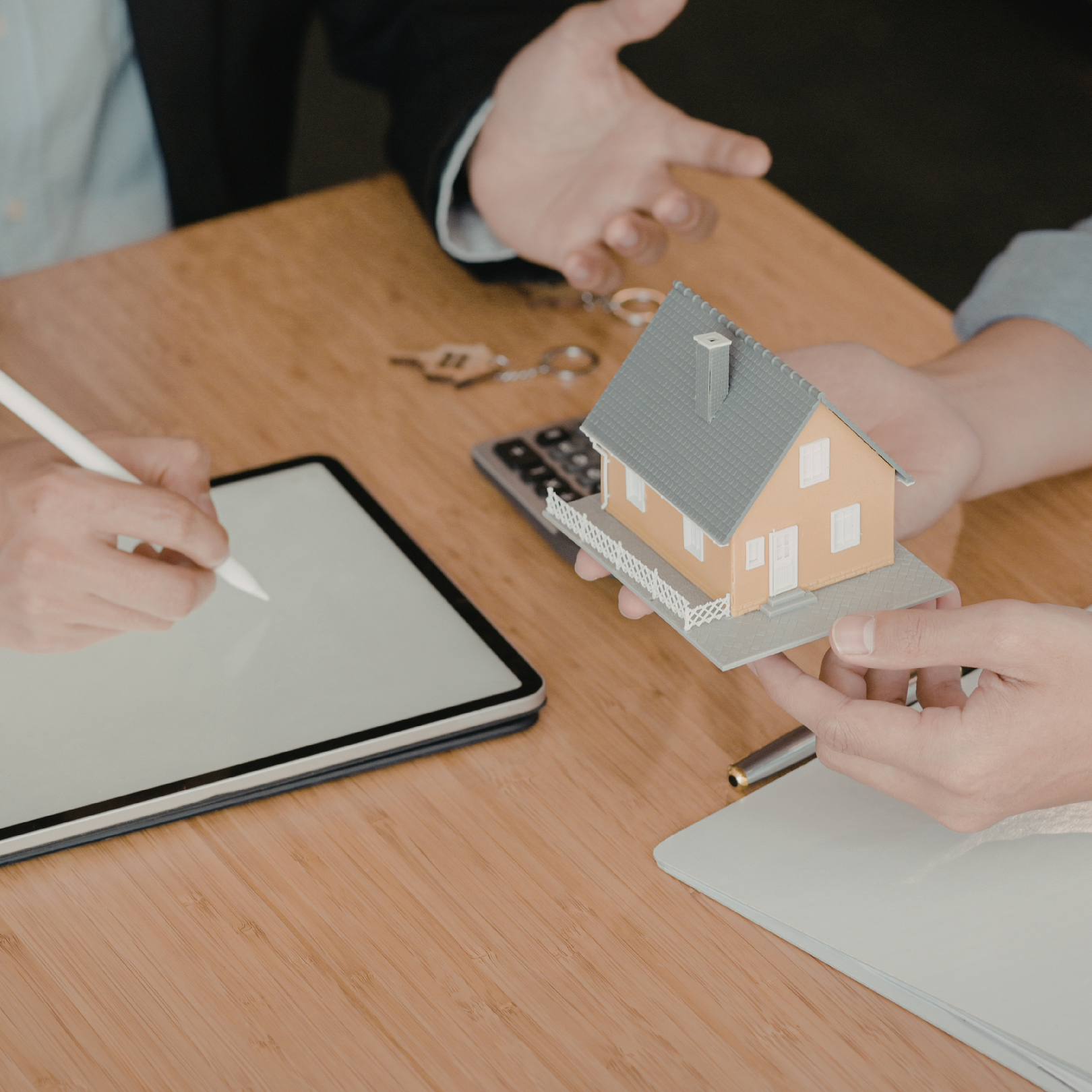 Two people in business suits shaking hands over a desk with law books and scales.