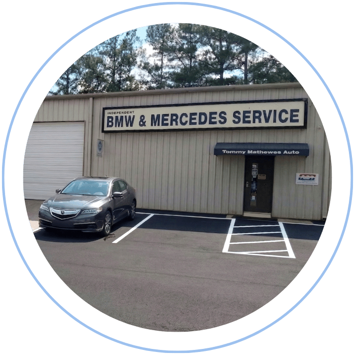 Blue car-shaped keychains displayed on the front desk, with a BMW mug and a Christian fish symbol sign in the background.