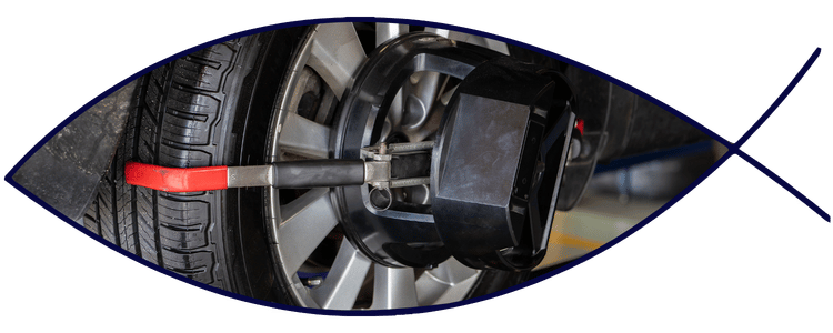 Blue car-shaped keychains displayed on the front desk, with a BMW mug and a Christian fish symbol sign in the background.