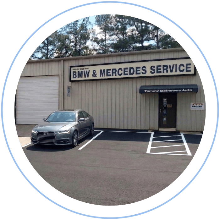 Blue car-shaped keychains displayed on the front desk, with a BMW mug and a Christian fish symbol sign in the background.