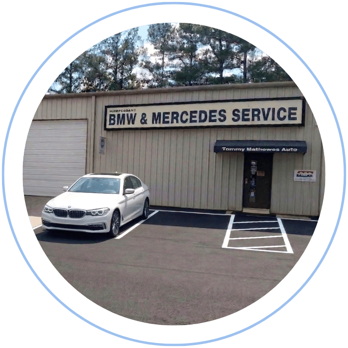 Blue car-shaped keychains displayed on the front desk, with a BMW mug and a Christian fish symbol sign in the background.