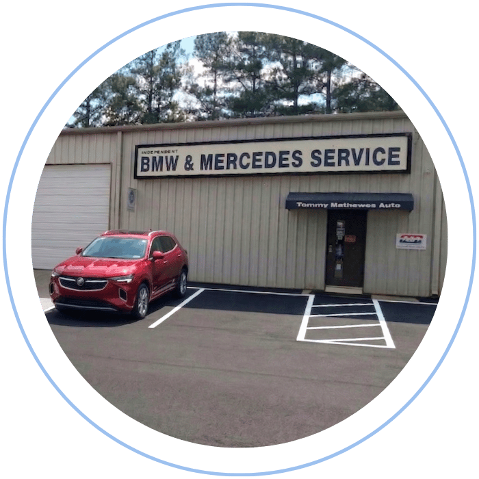 Blue car-shaped keychains displayed on the front desk, with a BMW mug and a Christian fish symbol sign in the background.