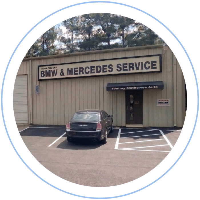Blue car-shaped keychains displayed on the front desk, with a BMW mug and a Christian fish symbol sign in the background.