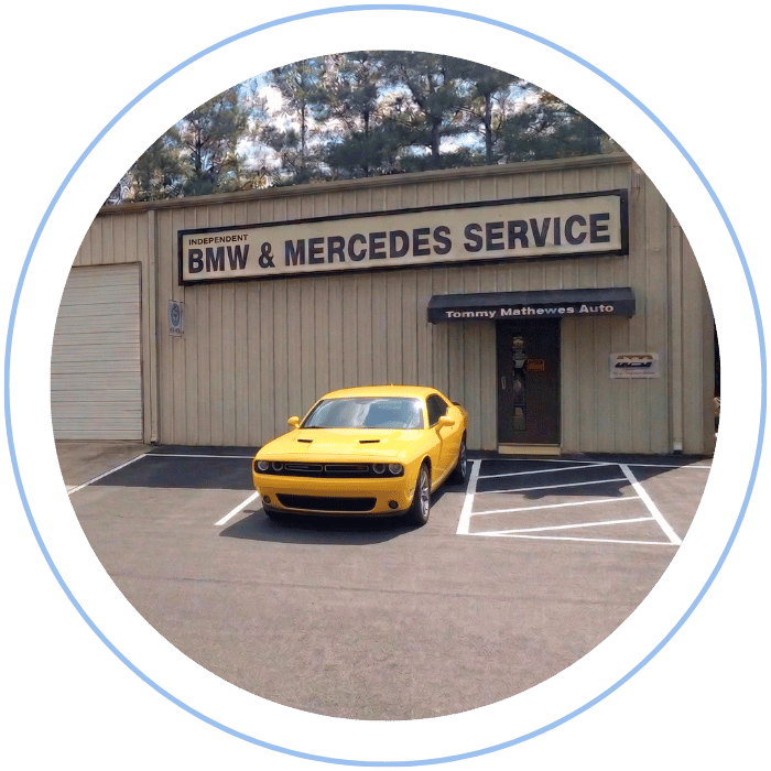Blue car-shaped keychains displayed on the front desk, with a BMW mug and a Christian fish symbol sign in the background.