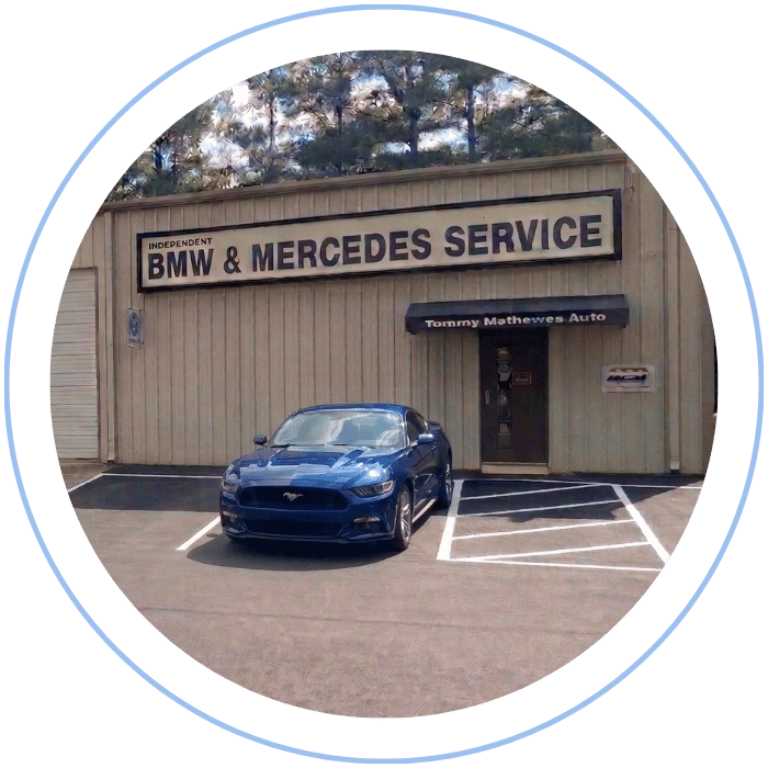 Blue car-shaped keychains displayed on the front desk, with a BMW mug and a Christian fish symbol sign in the background.