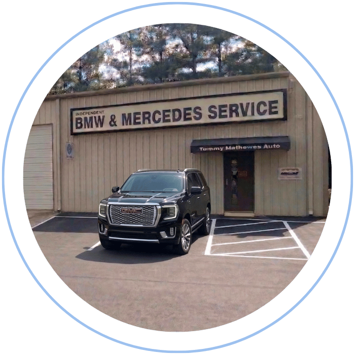 Blue car-shaped keychains displayed on the front desk, with a BMW mug and a Christian fish symbol sign in the background.