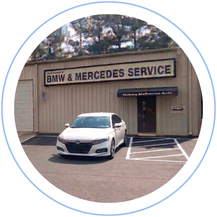 Blue car-shaped keychains displayed on the front desk, with a BMW mug and a Christian fish symbol sign in the background.