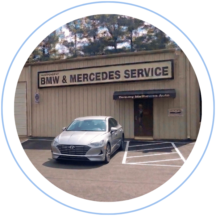 Blue car-shaped keychains displayed on the front desk, with a BMW mug and a Christian fish symbol sign in the background.