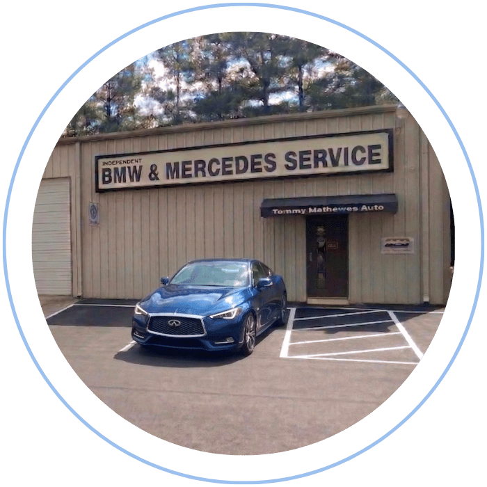 Blue car-shaped keychains displayed on the front desk, with a BMW mug and a Christian fish symbol sign in the background.