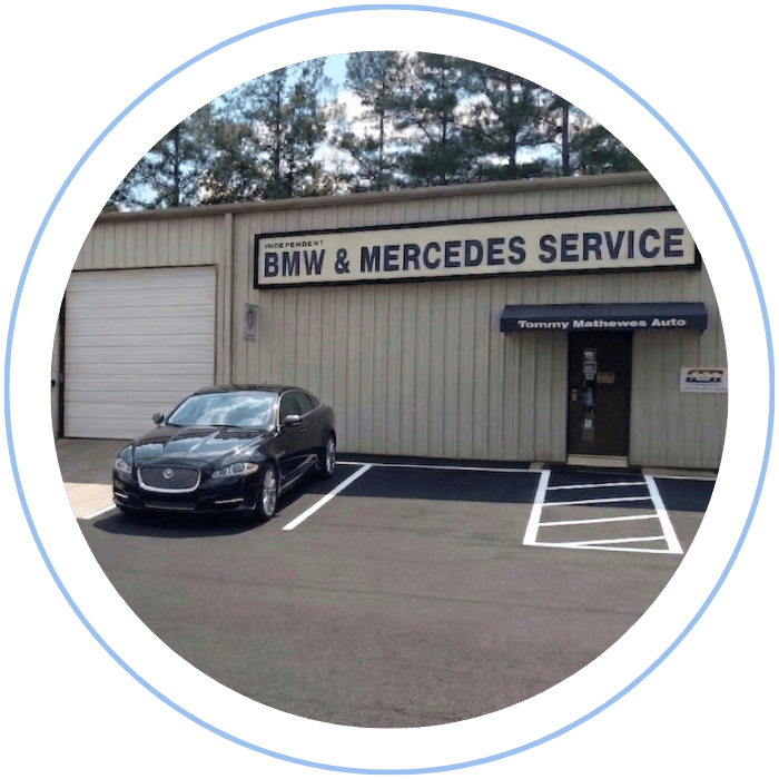 Blue car-shaped keychains displayed on the front desk, with a BMW mug and a Christian fish symbol sign in the background.