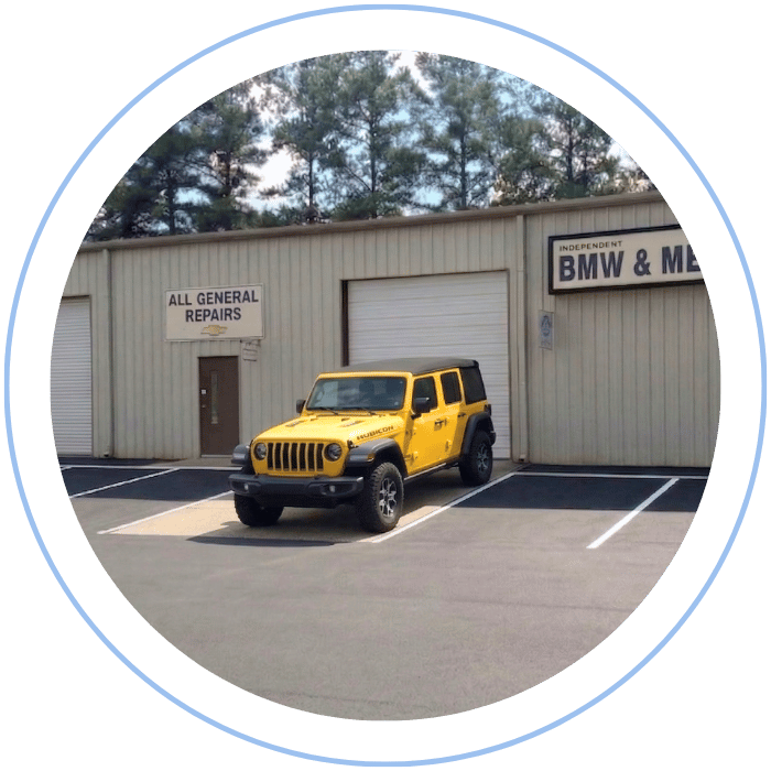 Blue car-shaped keychains displayed on the front desk, with a BMW mug and a Christian fish symbol sign in the background.