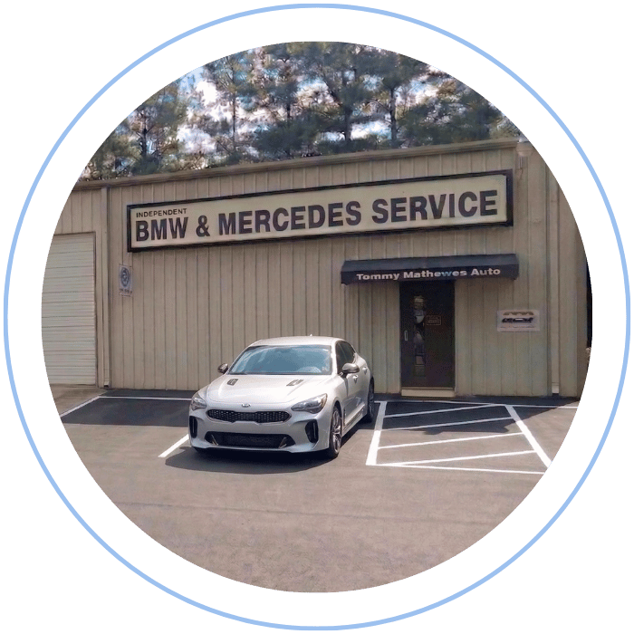 Blue car-shaped keychains displayed on the front desk, with a BMW mug and a Christian fish symbol sign in the background.