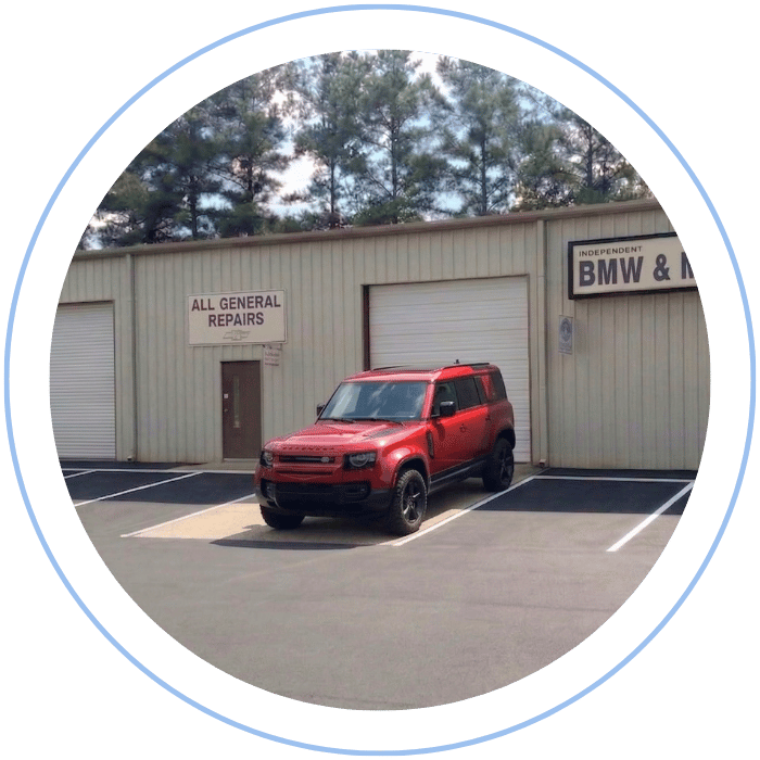 Blue car-shaped keychains displayed on the front desk, with a BMW mug and a Christian fish symbol sign in the background.