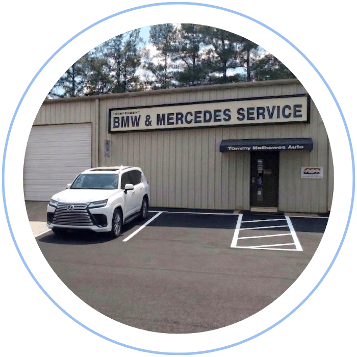 Blue car-shaped keychains displayed on the front desk, with a BMW mug and a Christian fish symbol sign in the background.