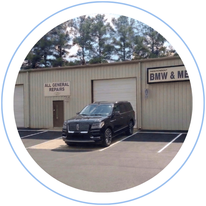 Blue car-shaped keychains displayed on the front desk, with a BMW mug and a Christian fish symbol sign in the background.