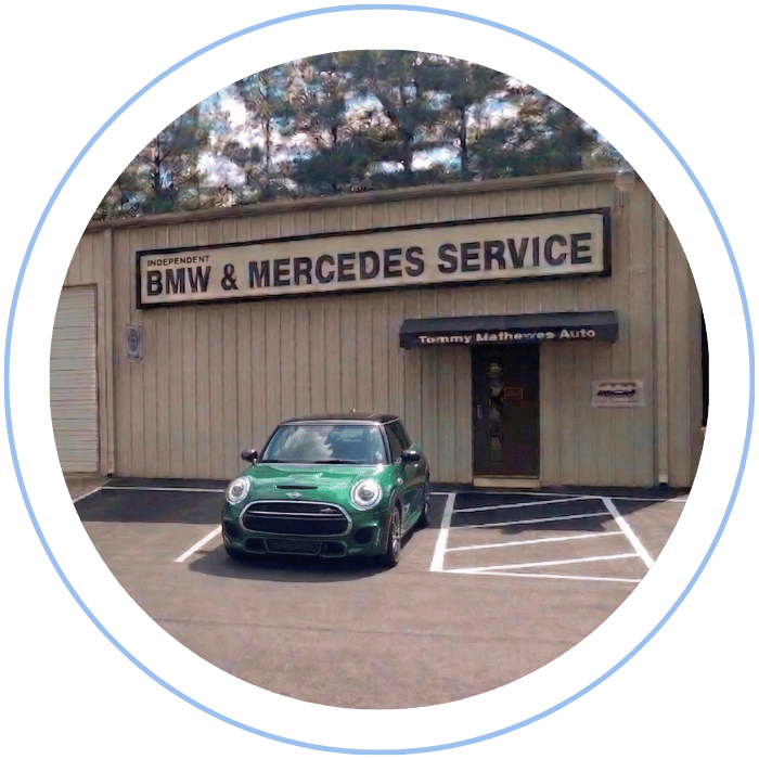 Blue car-shaped keychains displayed on the front desk, with a BMW mug and a Christian fish symbol sign in the background.