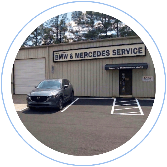 Blue car-shaped keychains displayed on the front desk, with a BMW mug and a Christian fish symbol sign in the background.