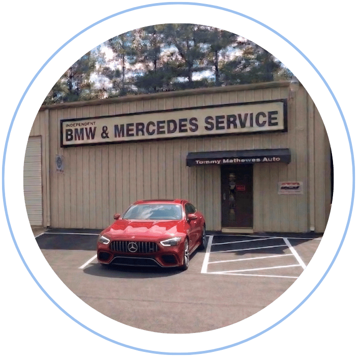 Blue car-shaped keychains displayed on the front desk, with a BMW mug and a Christian fish symbol sign in the background.