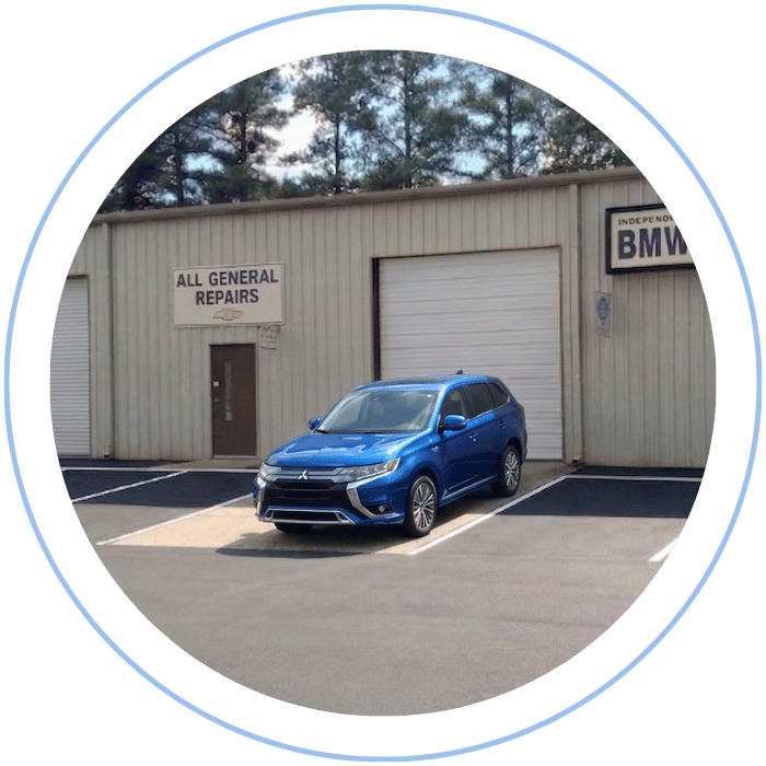 Blue car-shaped keychains displayed on the front desk, with a BMW mug and a Christian fish symbol sign in the background.