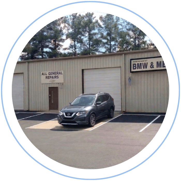 Blue car-shaped keychains displayed on the front desk, with a BMW mug and a Christian fish symbol sign in the background.
