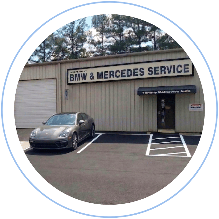 Blue car-shaped keychains displayed on the front desk, with a BMW mug and a Christian fish symbol sign in the background.