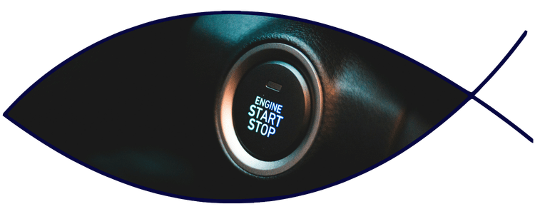 Blue car-shaped keychains displayed on the front desk, with a BMW mug and a Christian fish symbol sign in the background.