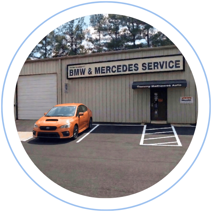 Blue car-shaped keychains displayed on the front desk, with a BMW mug and a Christian fish symbol sign in the background.