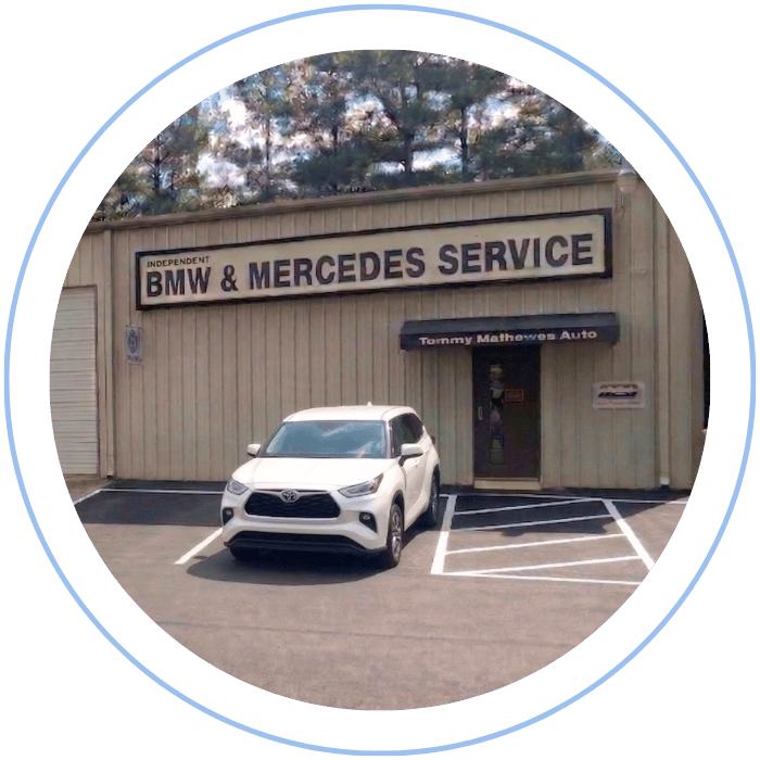 Blue car-shaped keychains displayed on the front desk, with a BMW mug and a Christian fish symbol sign in the background.