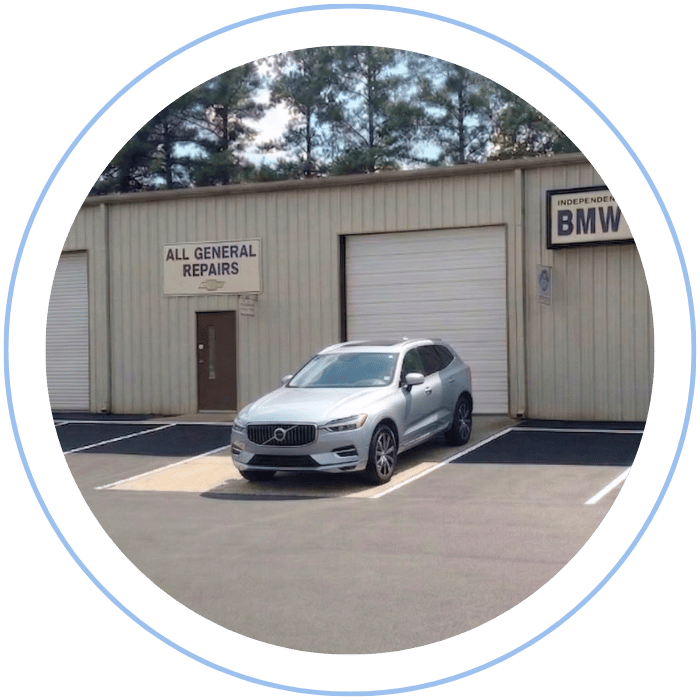 Blue car-shaped keychains displayed on the front desk, with a BMW mug and a Christian fish symbol sign in the background.