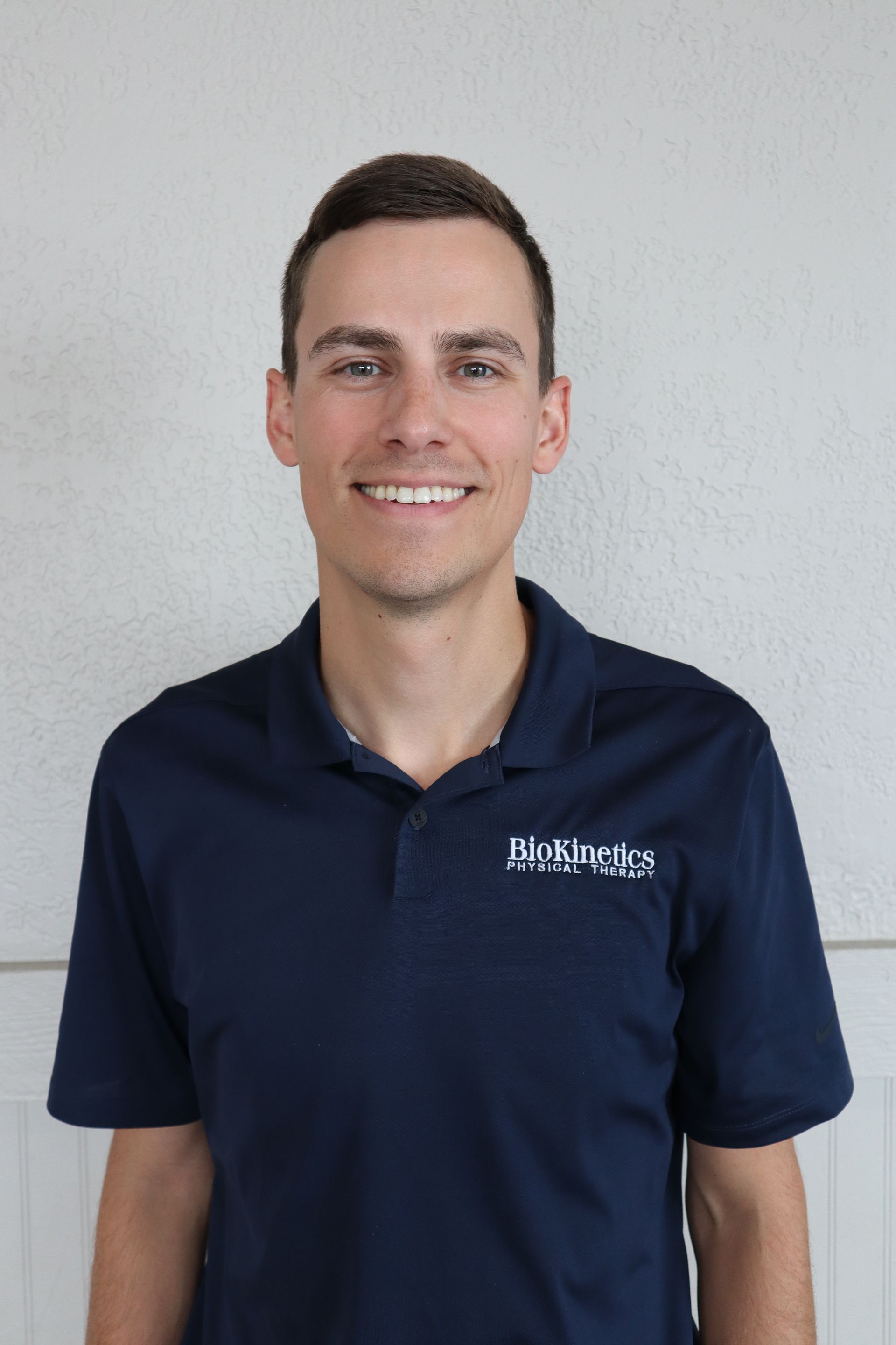 A man wearing a blue polo shirt is smiling for the camera.