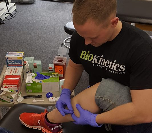 A man wearing a black shirt that says biokinetics on it