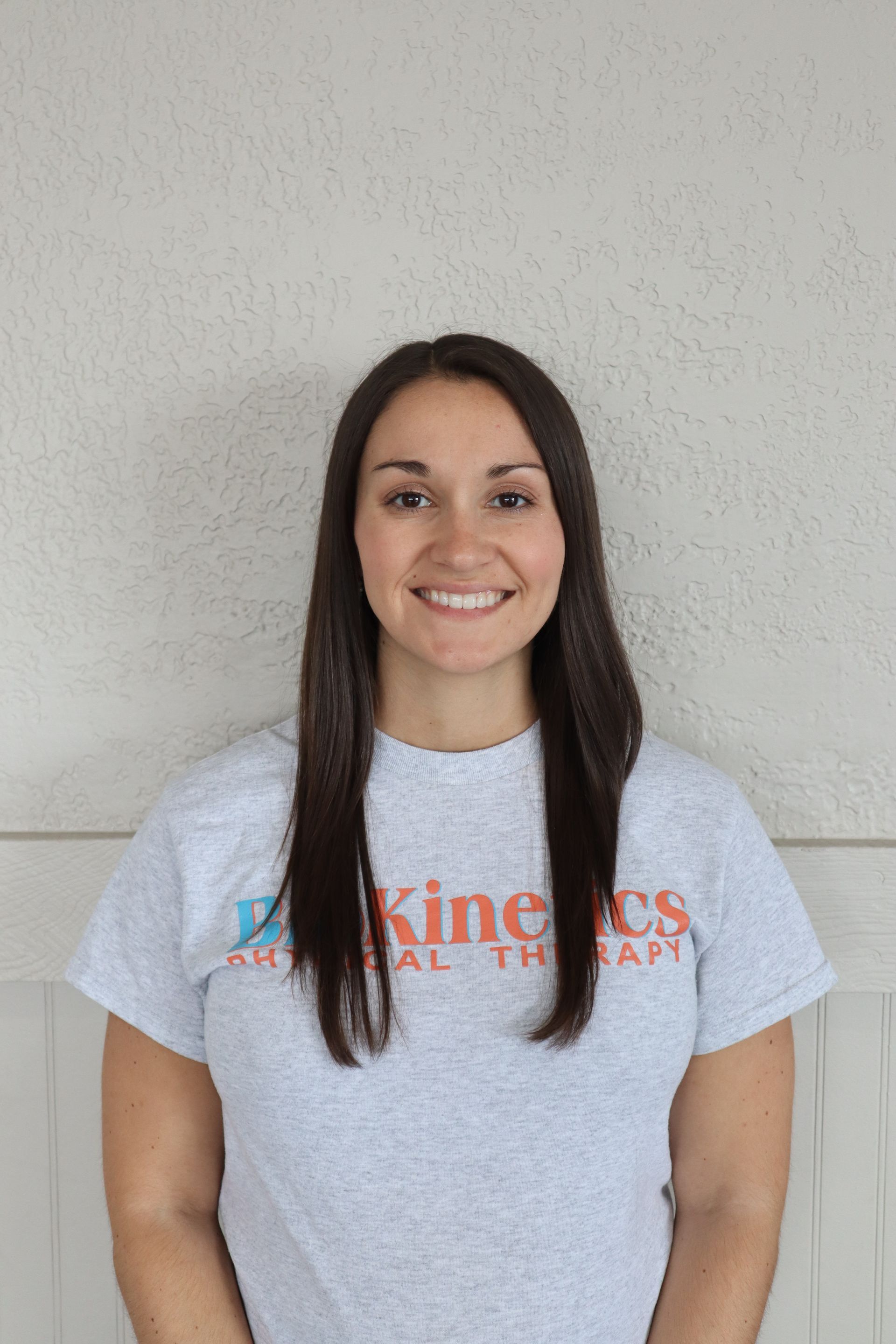 A woman wearing a gray t-shirt is smiling for the camera.