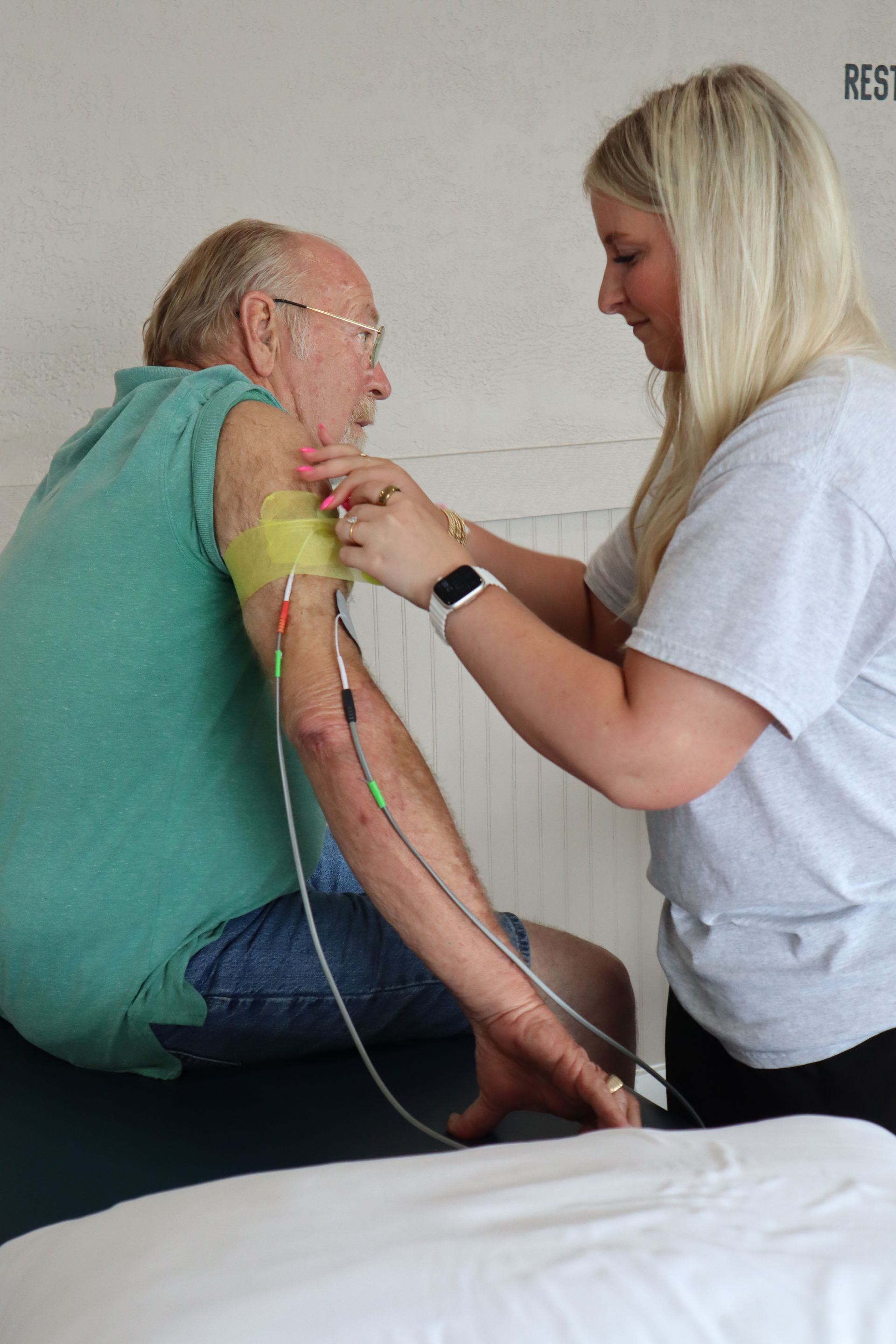 A woman is examining an older man 's arm.