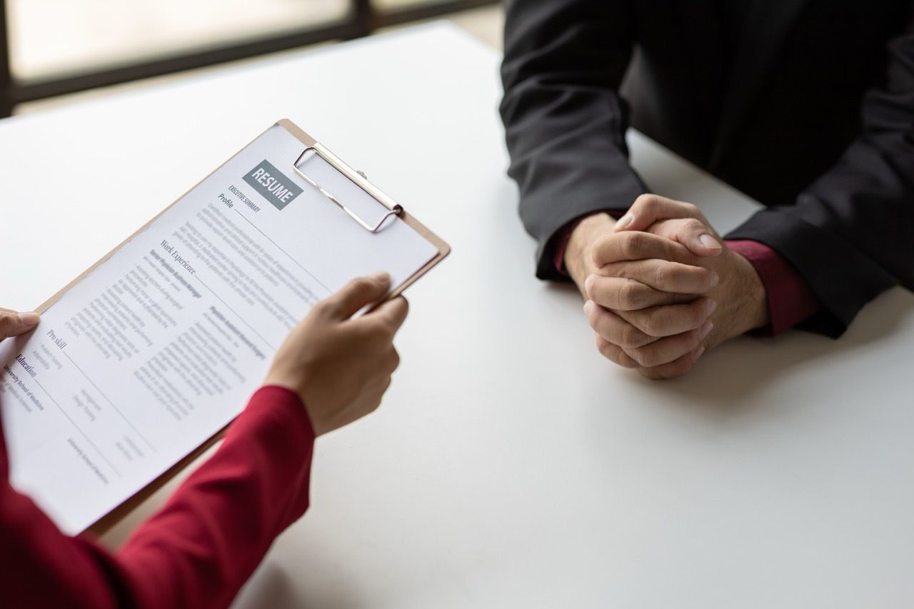 Two women in a job interview and the employer is reviewing a resume