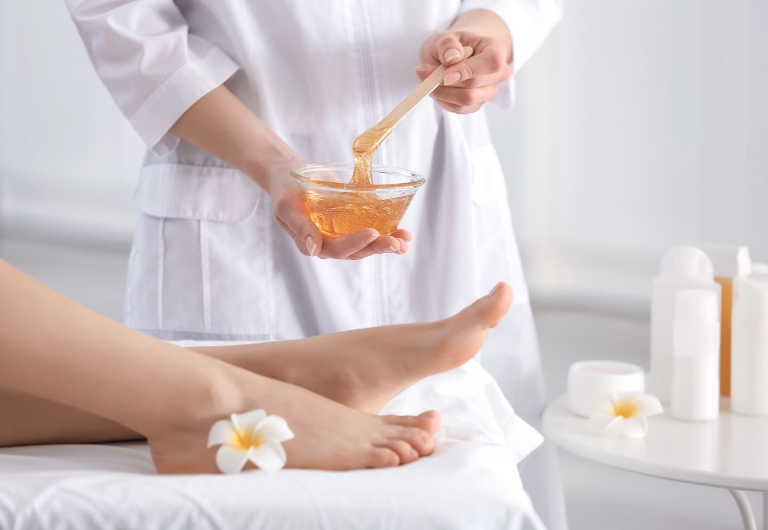 beautician waxing female legs in spa center