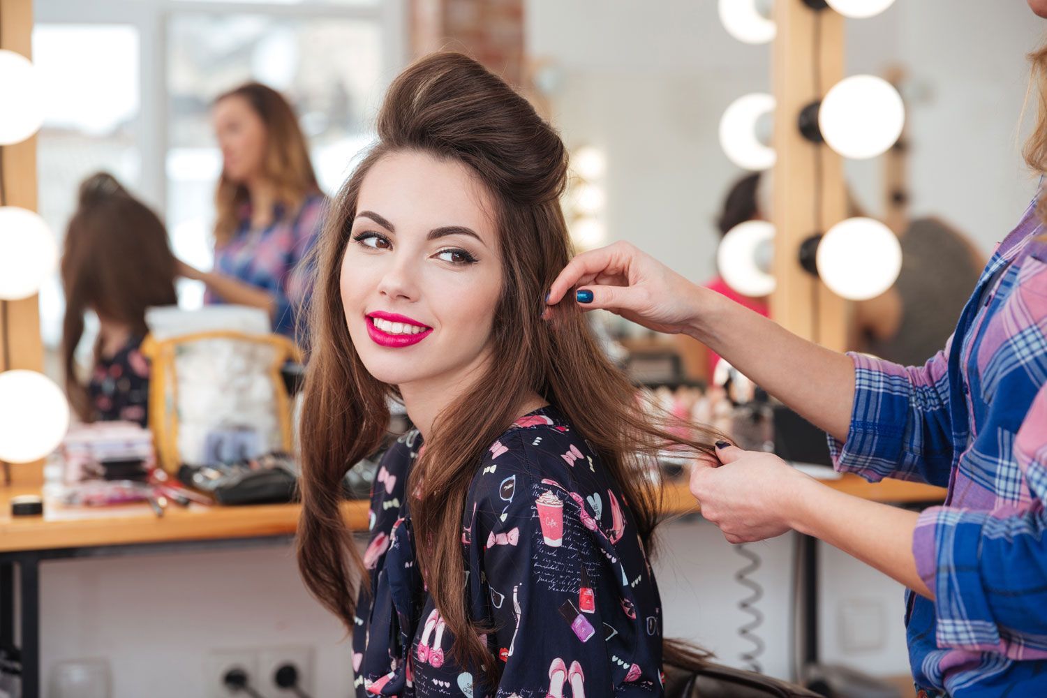 Female hairdresser standing and making hairstyle to lovely young woman in beauty salon