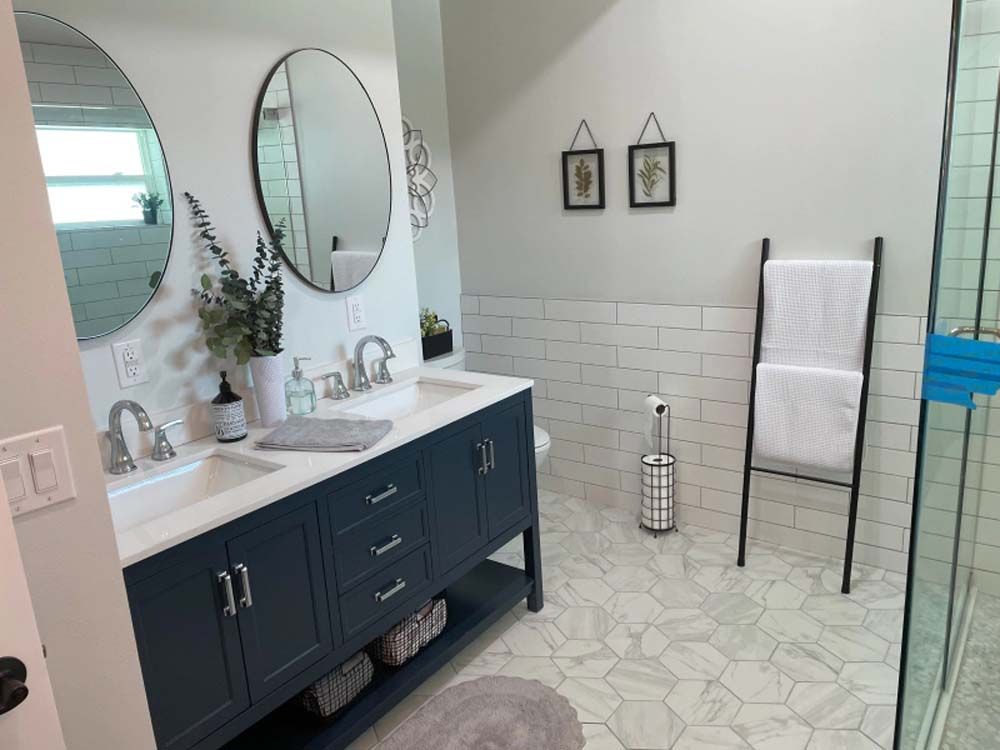 A bathroom with two sinks , two mirrors and a walk in shower.