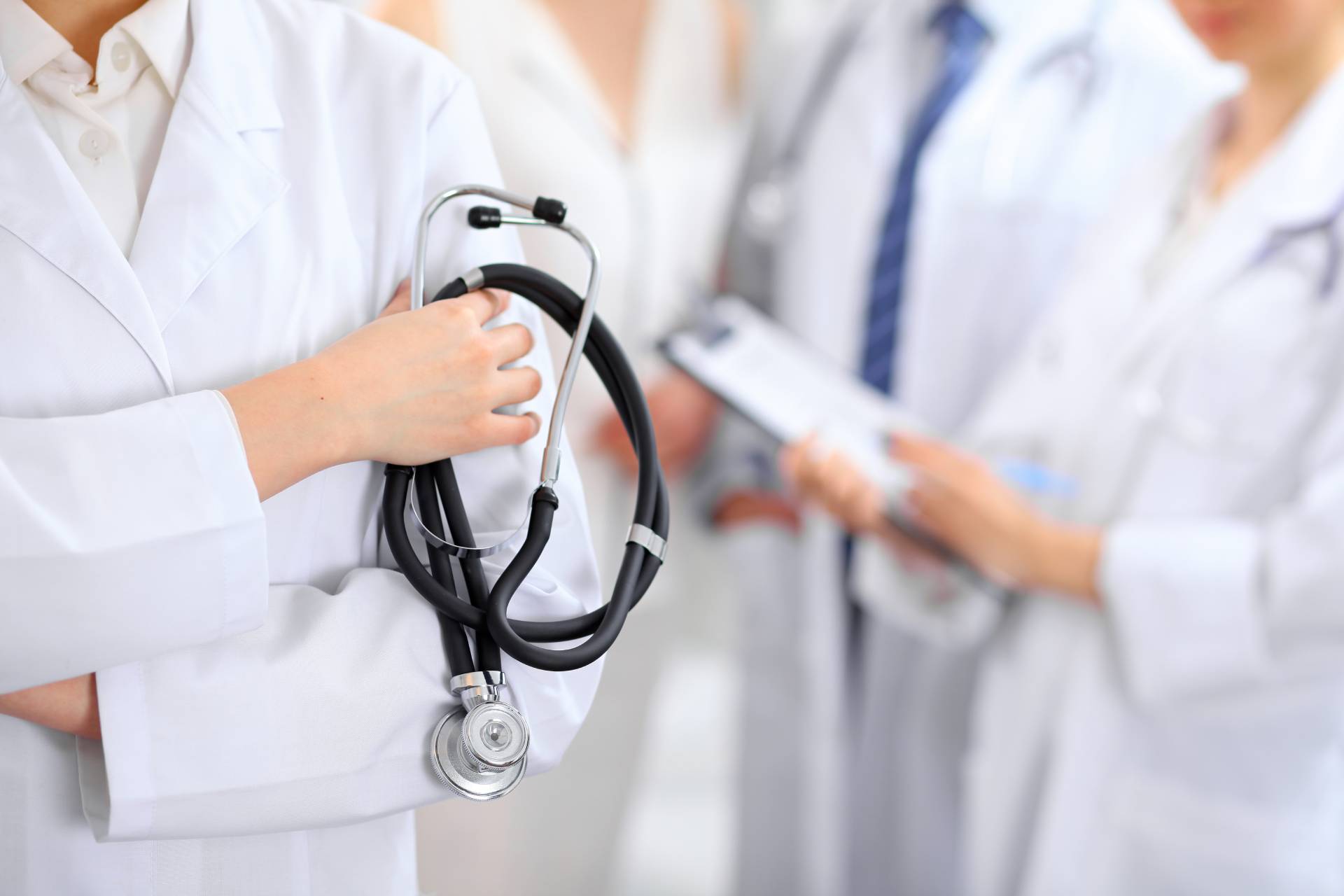 Un medico tiene in mano uno stetoscopio di fronte a un gruppo di dottori.