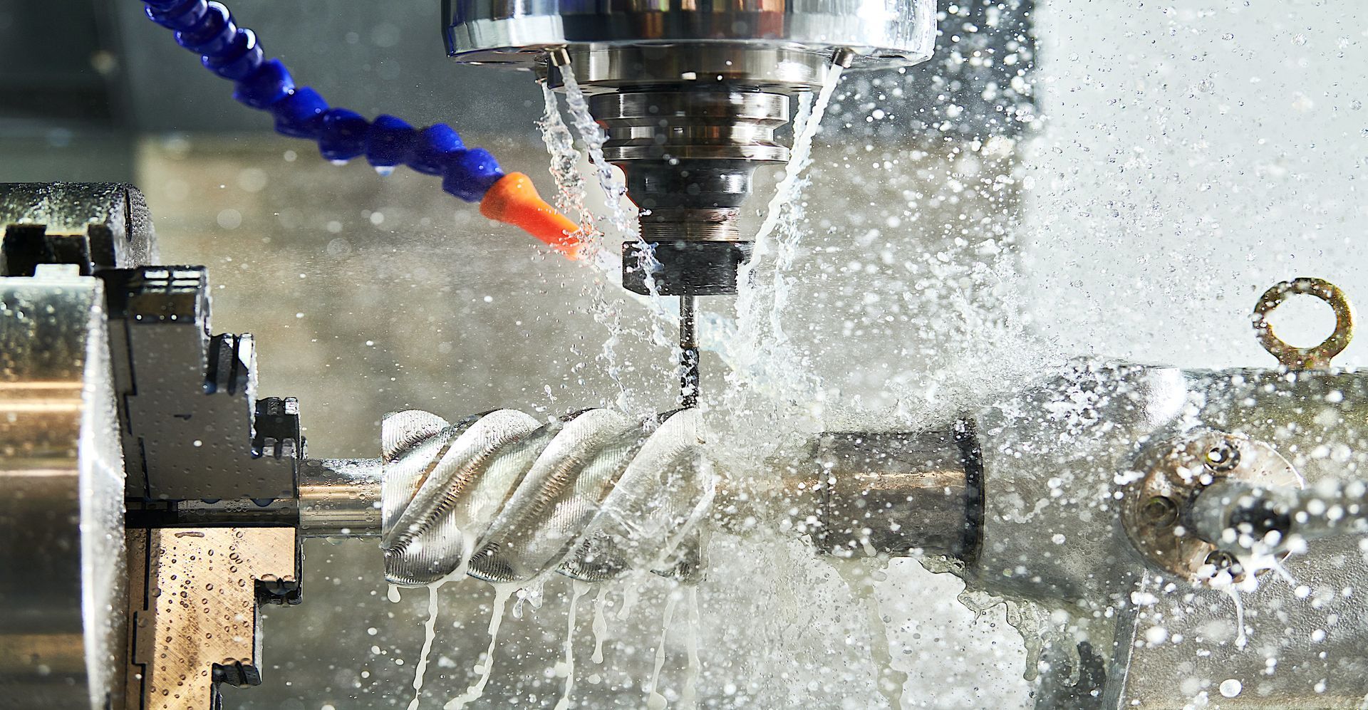 CNC machine milling metal, coolant spraying, creating a spiral.