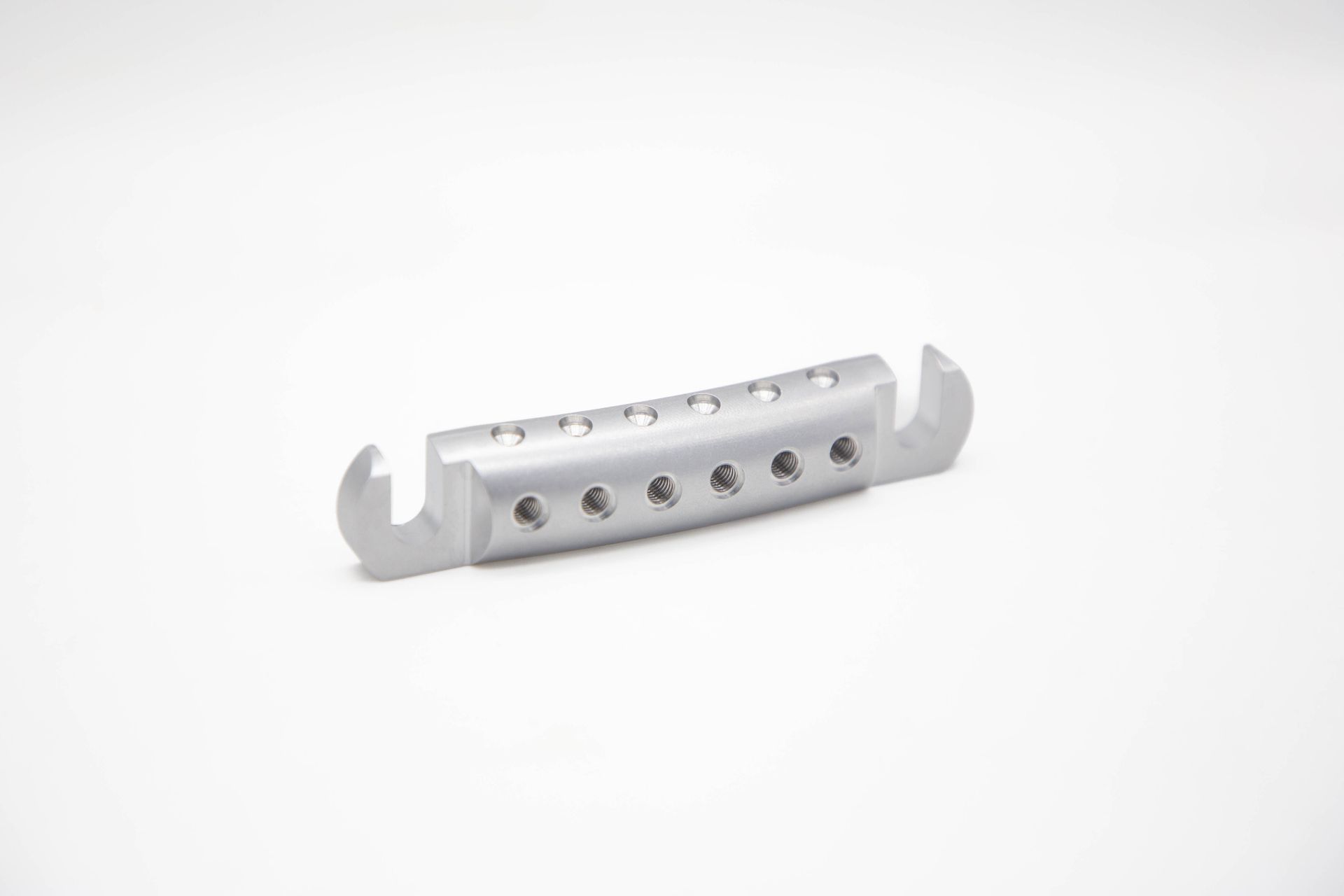 Silver guitar bridge, a component for stringed instruments.