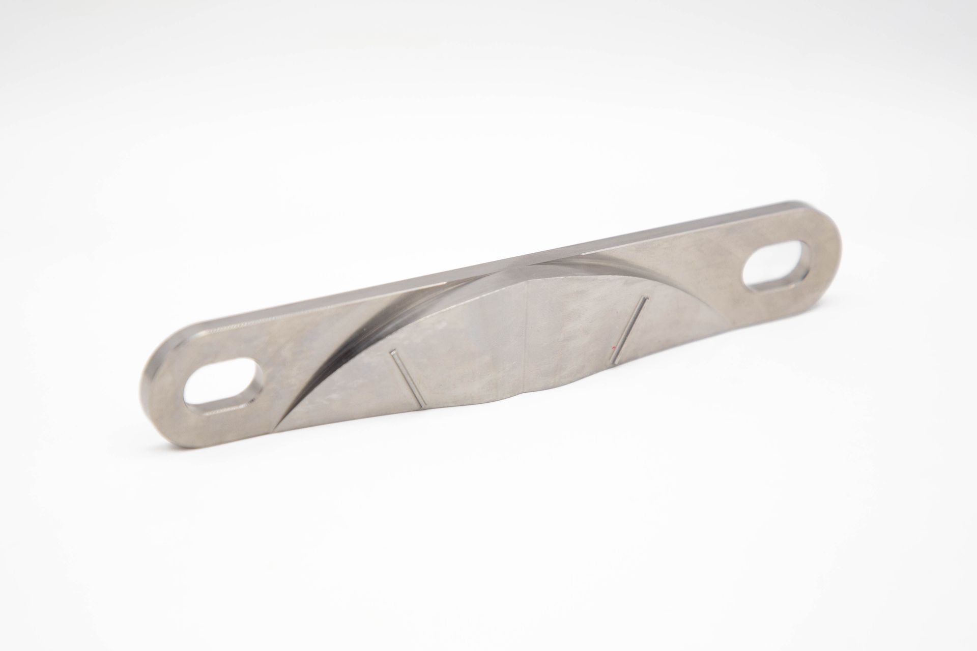 A metal, twisted bar with holes at each end, lying on a white surface.