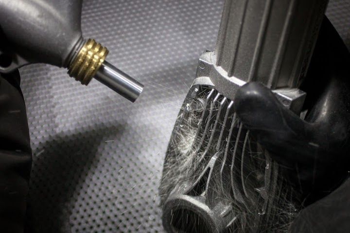 Person in protective gear sandblasting inside a metal enclosure.