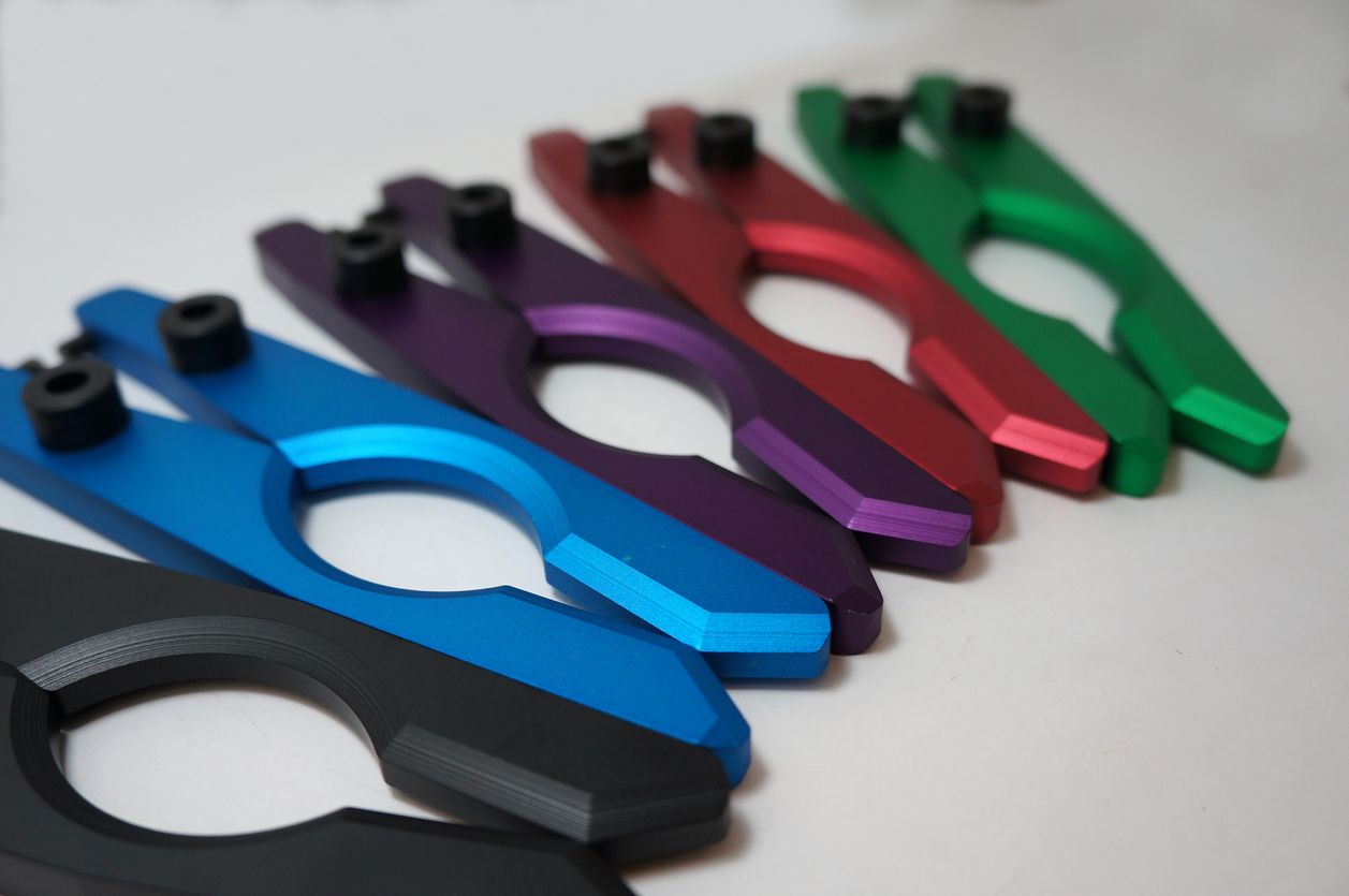 Six colorful metal tools with black screws, arranged on a white surface.