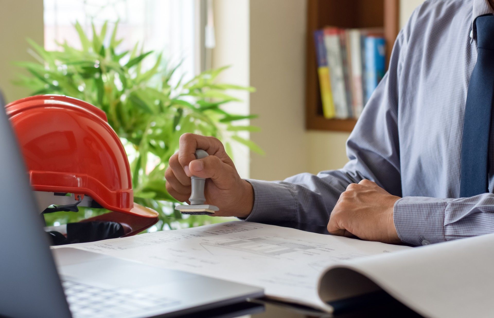 A man is sitting at a desk holding a stamp.